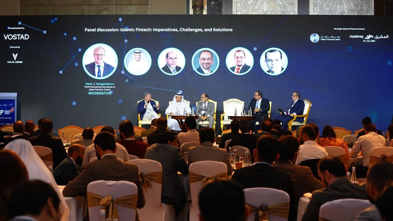 A panel of speakers seated on stage in front of a seated audience