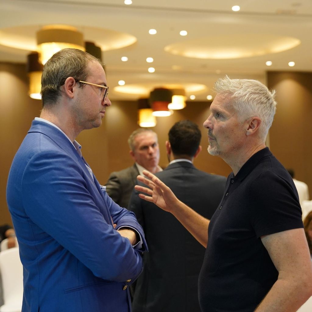 Two delegates in conversation during a break at a conference